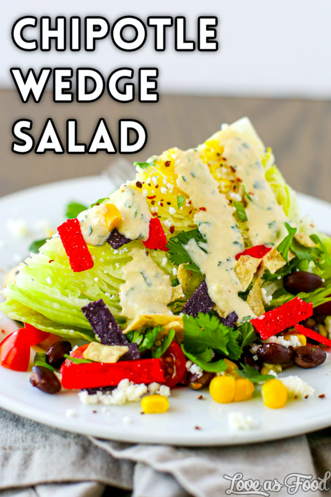 A wedge of iceberg lettuce with corn, black beans, cilantro, green onion, a lime wedge, queso fresco, tortilla strips and creamy chipotle tomatillo dressing.